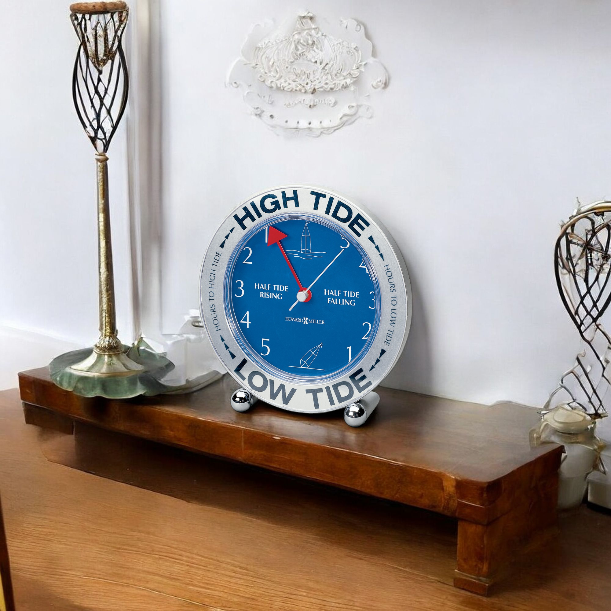 A blue tide clock displaying high and low tide indicators on a wooden shelf.