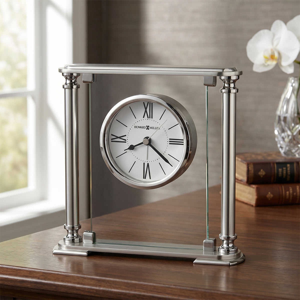 Silver table clock with glass on a wooden surface near a window