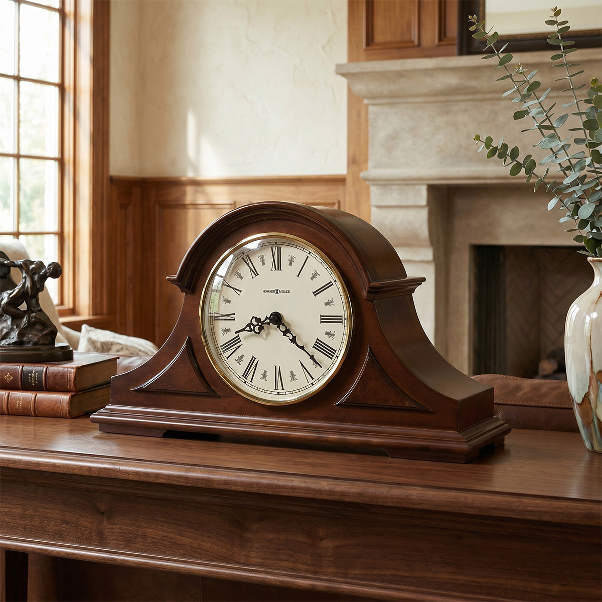 Wooden mantel clock on a wooden surface with a fireplace and books in the background
