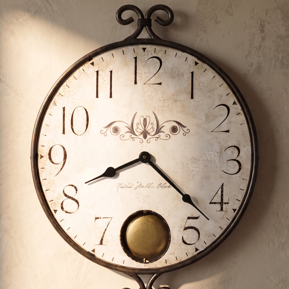 A round vintage-style wall clock with a distressed off-white face, black numerals, black ornate frame, and a brass bobbin wheel at the bottom, mounted on a textured beige wall.