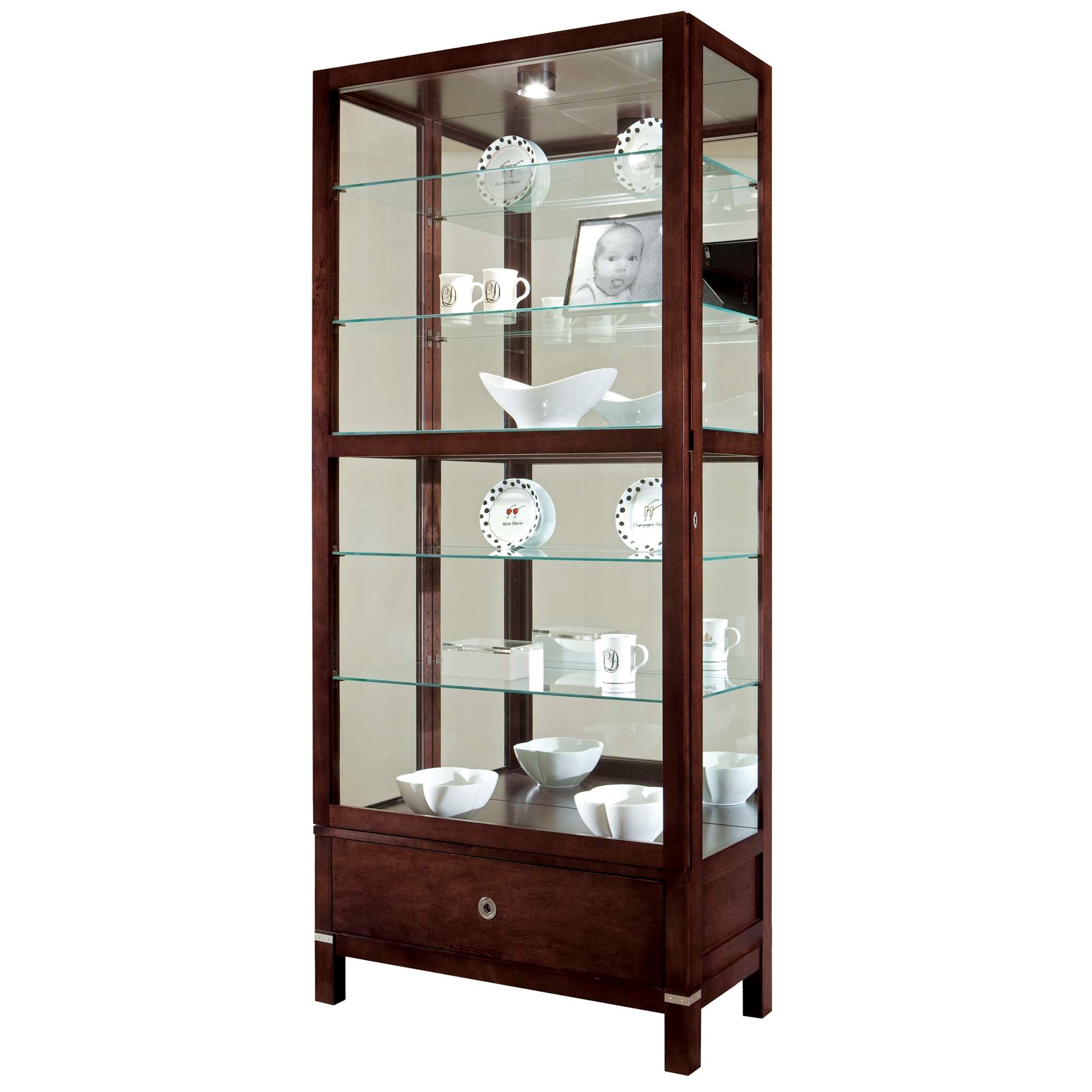 A tall wooden display cabinet with glass shelves showcasing various white ceramic dishes and decorative items.