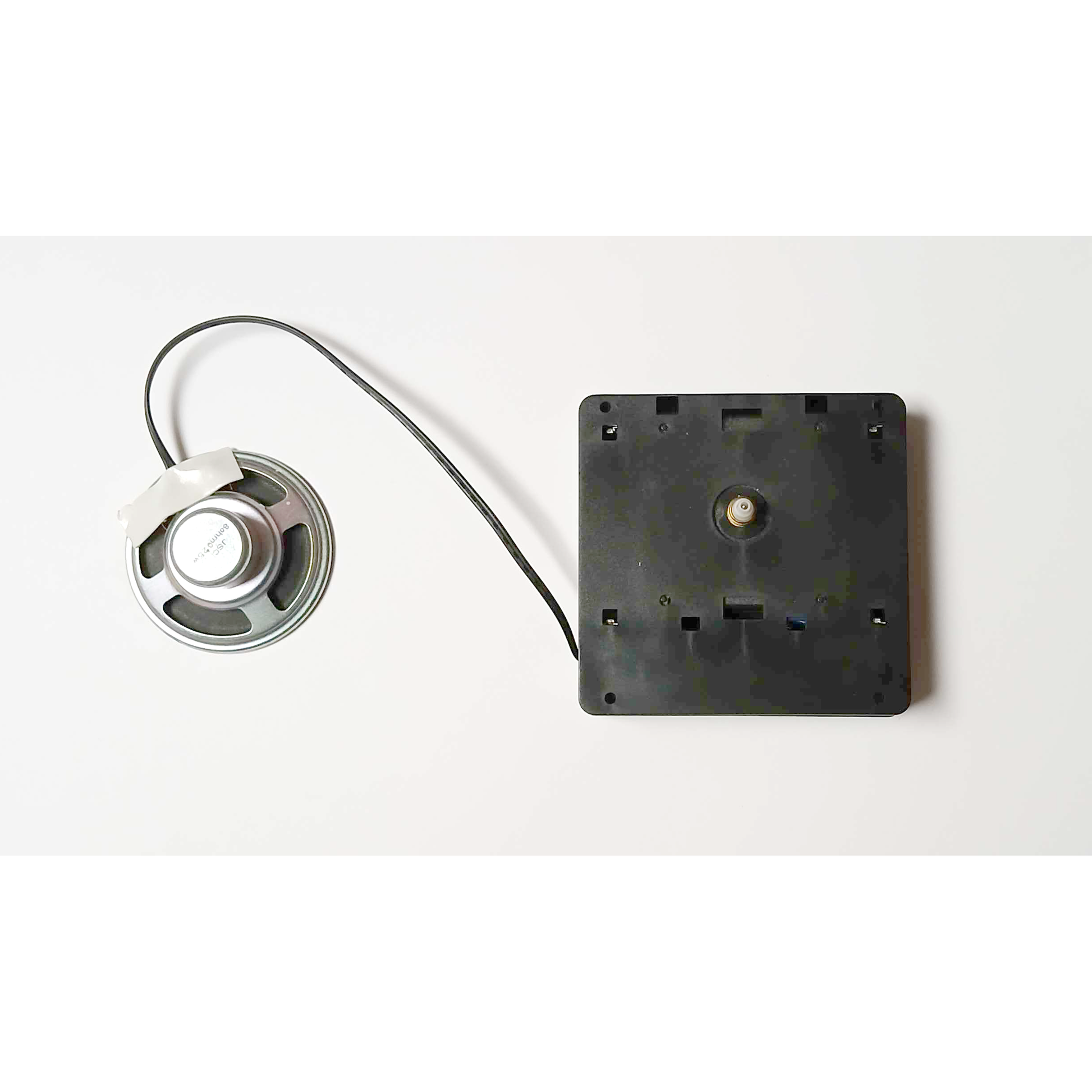 A speaker connected to a black mount with a cable.