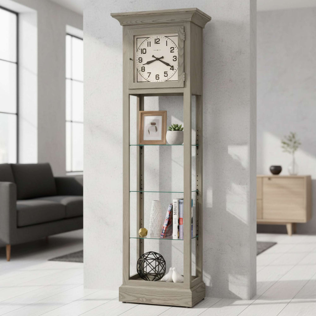 A tall, gray display cabinet with a clock at the top, featuring glass shelves and decorative items, in a modern living room setting.