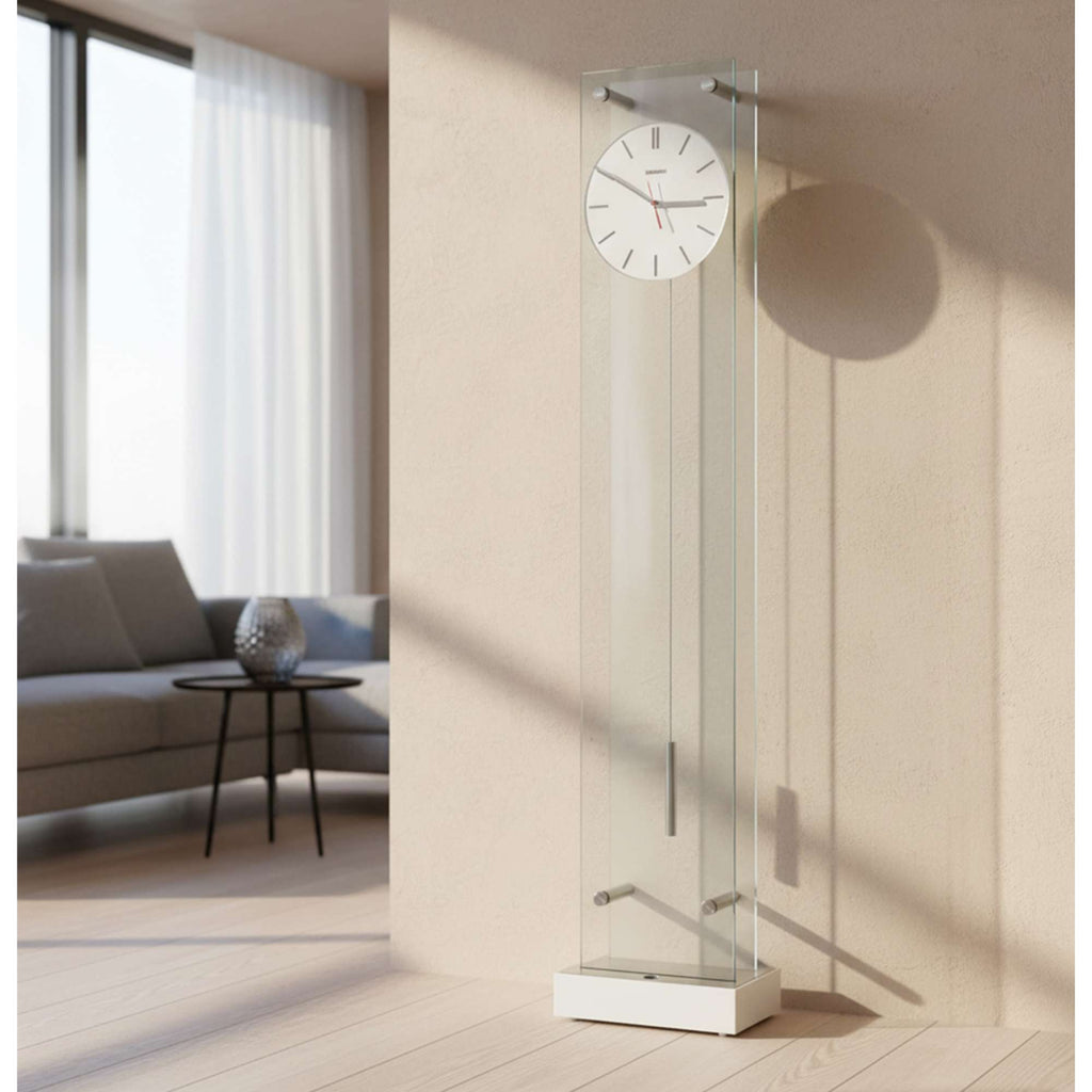 Modern glass floor clock against a beige wall in a well-lit room