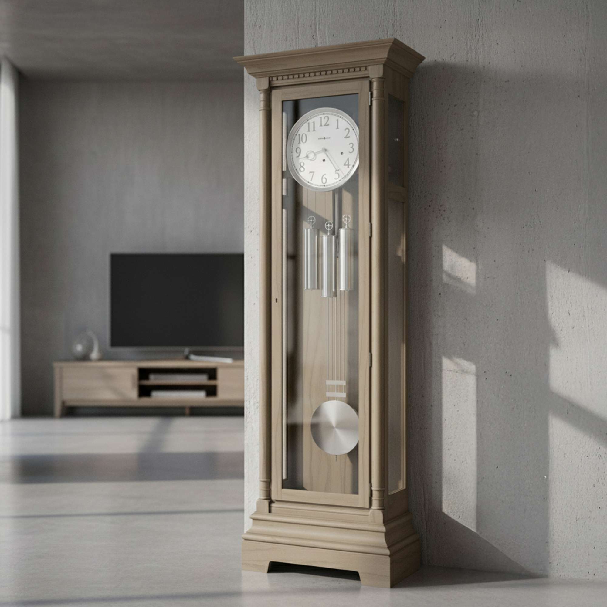 A tall brass grandfather clock with a glass front, placed in a modern living room setting.