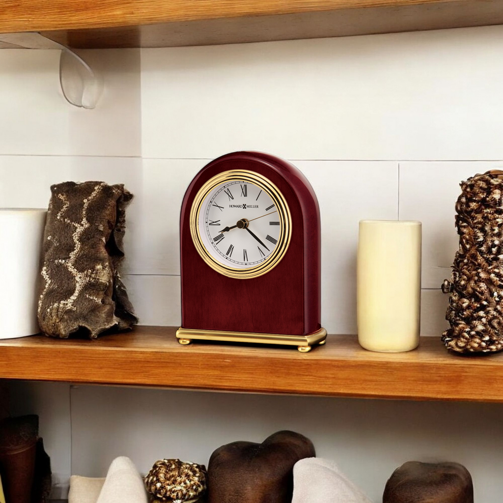 A vintage-style clock placed on a wooden shelf among decorative objects.