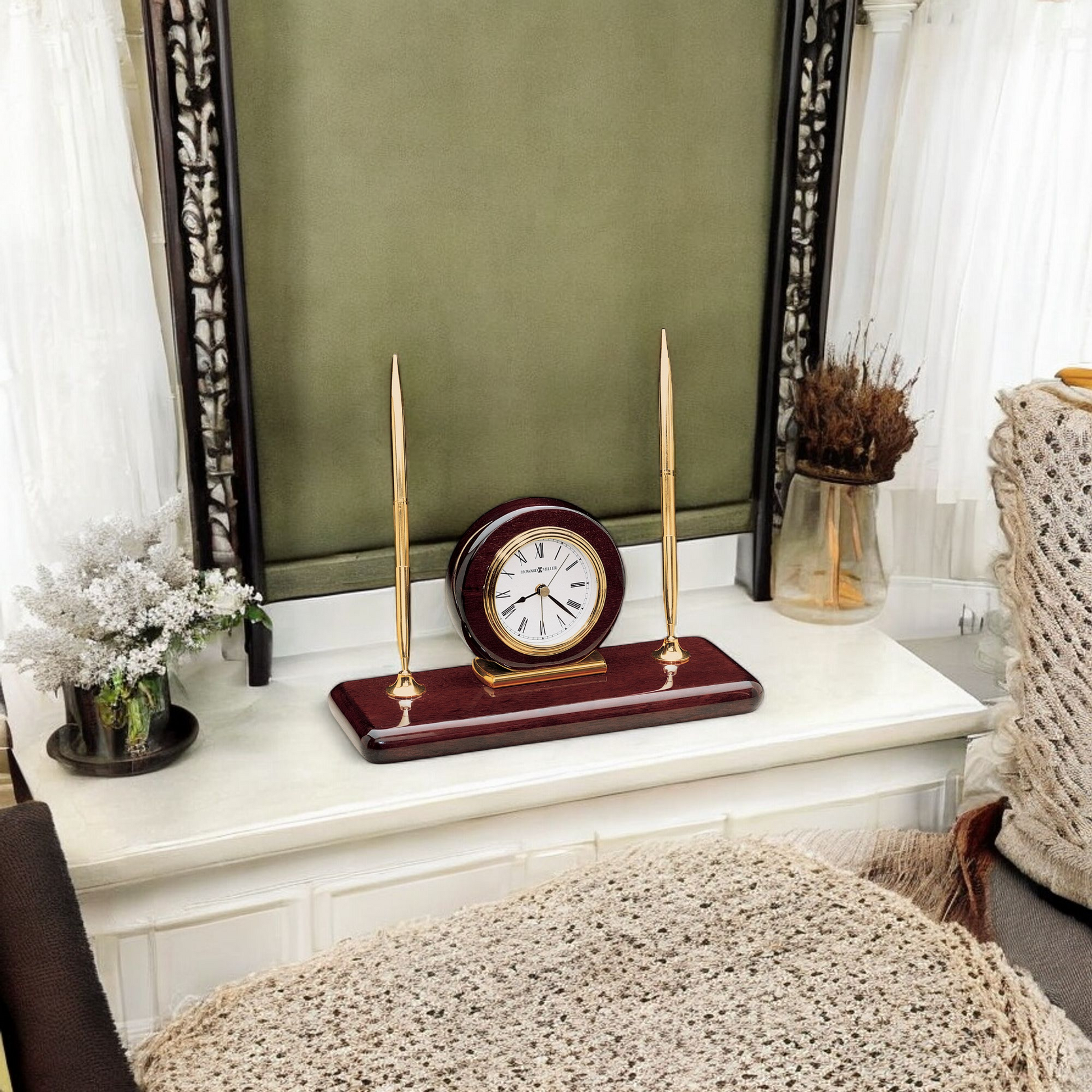 A decorative mantel clock with gold accents and two candle holders on a white surface, surrounded by a cozy interior.
