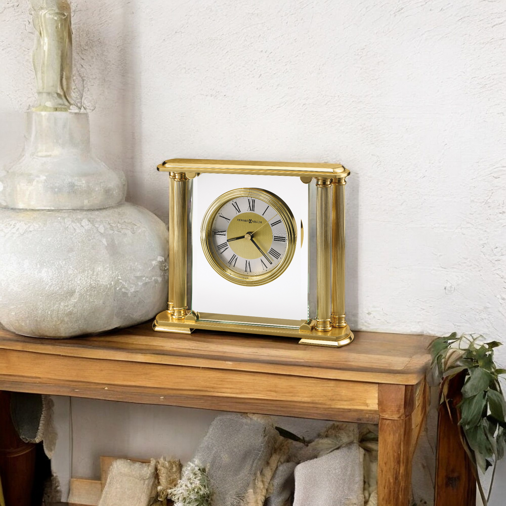 Elegant gold desk clock on a wooden table with decorative items.