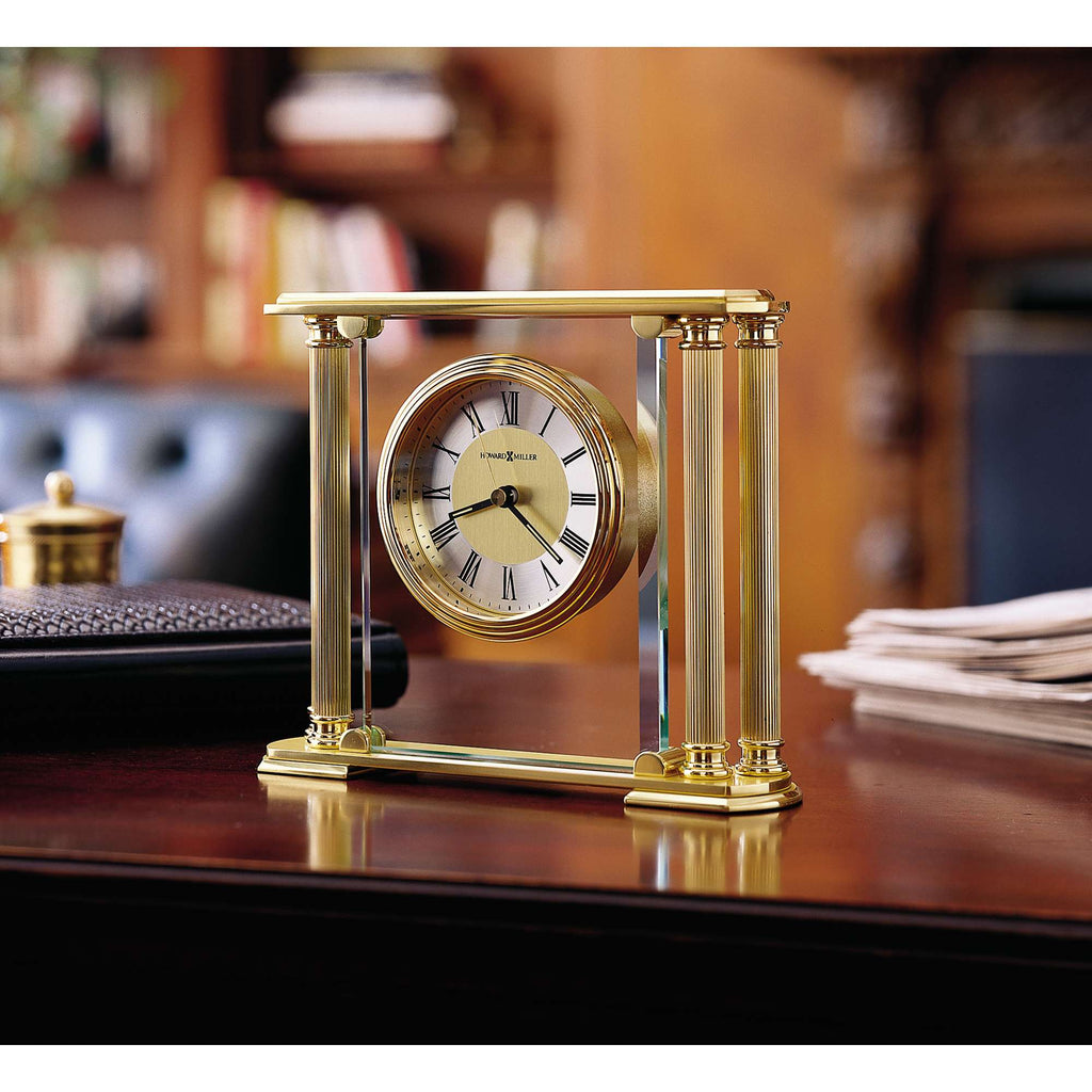 A decorative gold clock on a wooden desk.