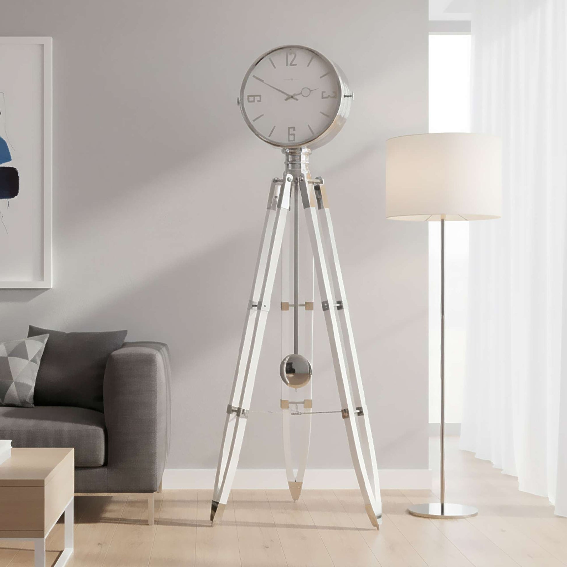 A modern tripod clock stands in a stylish living room beside a lamp and a gray sofa.
