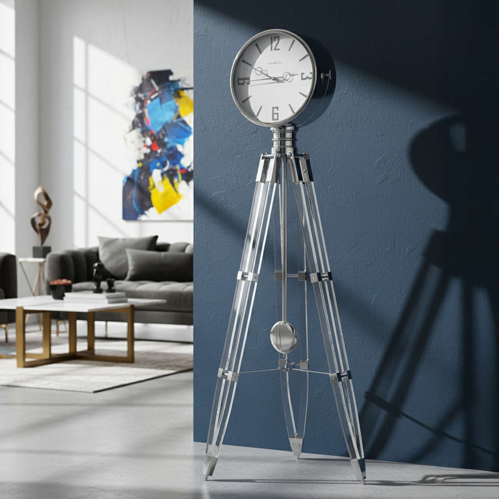 A stylish modern clock on a tripod stand against a blue wall in a contemporary living room.