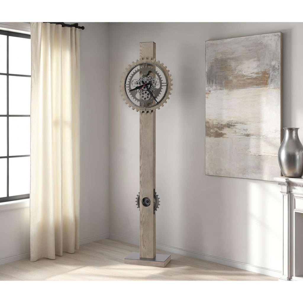 A tall, modern wall clock with a gear design and wooden finish, placed in a bright room with curtains and wall art.