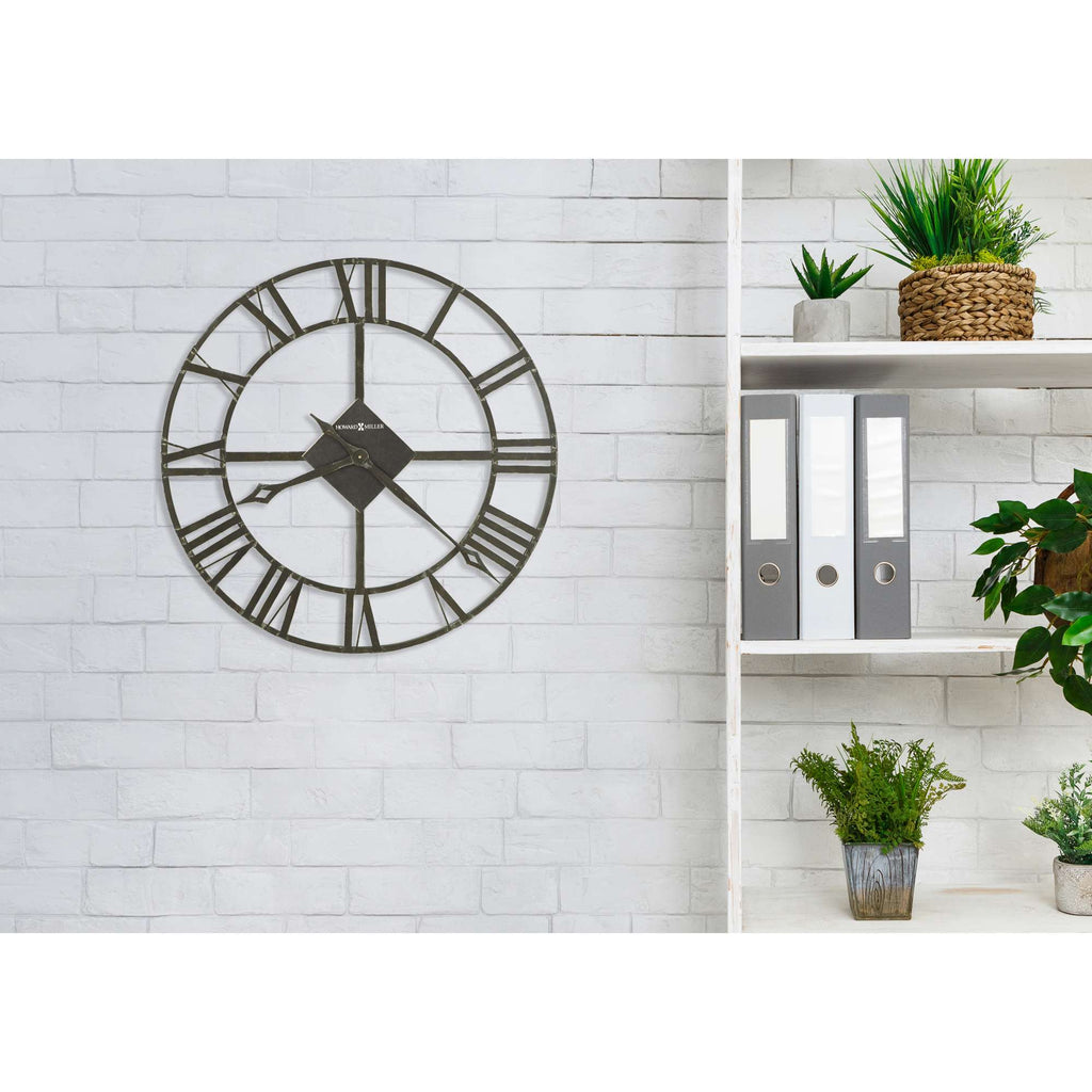 A stylish wall clock with Roman numerals hanging on a white brick wall, beside a minimalist shelf with plants and storage boxes.