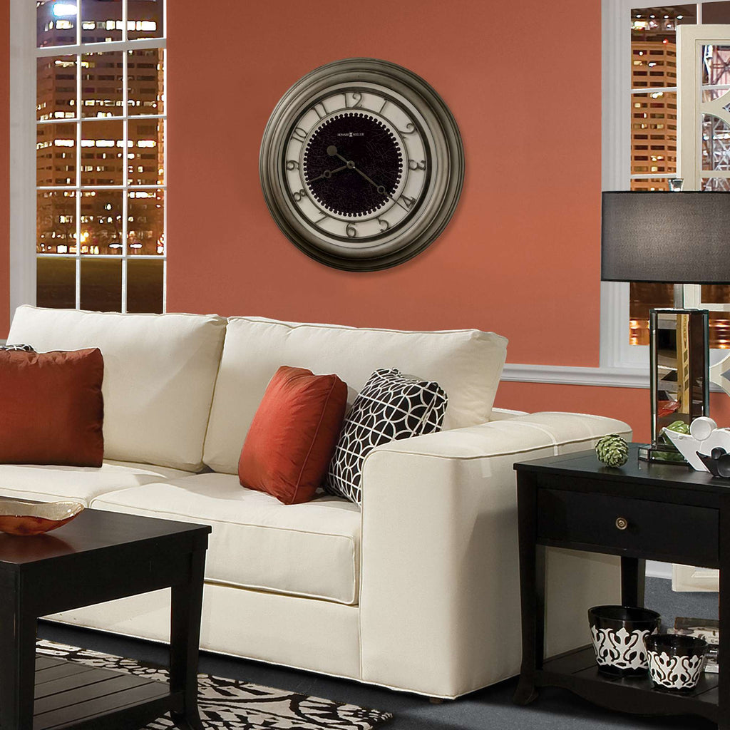 Living room interior featuring a clock on the wall above a white sofa with decorative pillows and a dark side table.