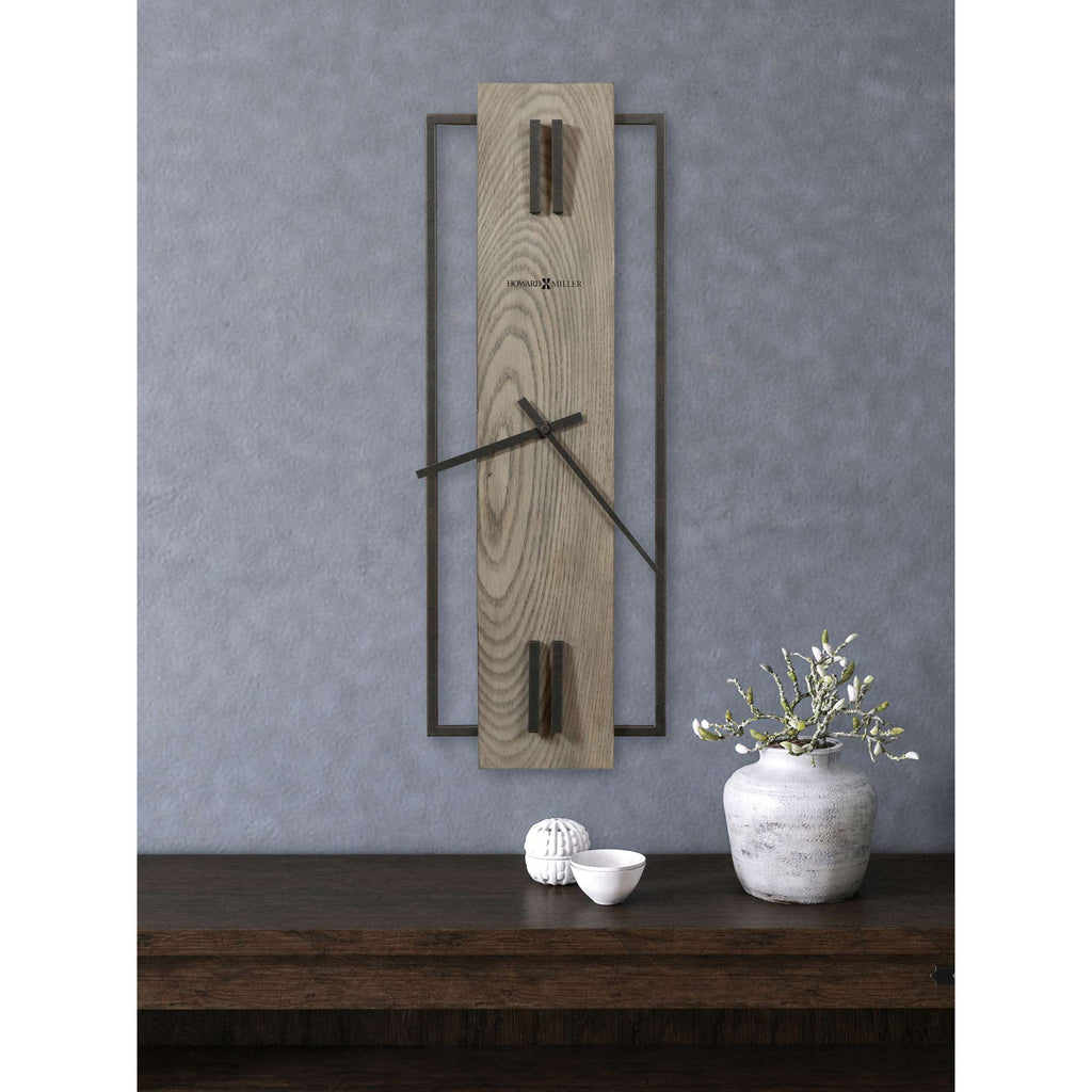 Modern wall clock on a gray wall above a wooden table with decorative items.