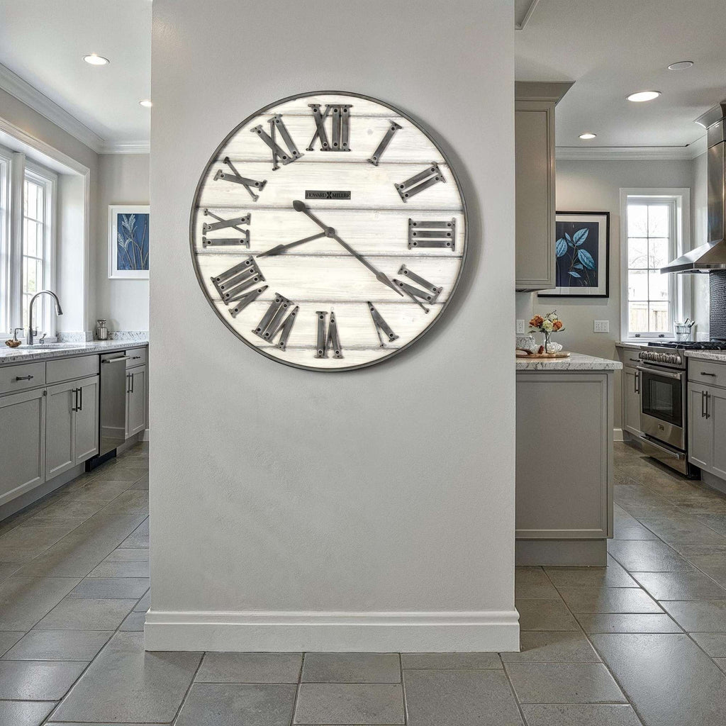 A large round wall clock with Roman numerals on a light-colored wall in a modern kitchen.