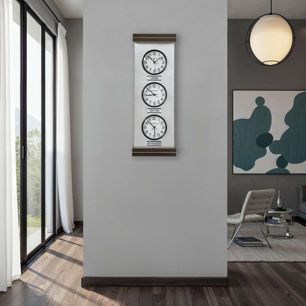 A modern interior featuring a wall-mounted clock with three time zones, alongside large windows and contemporary decor.