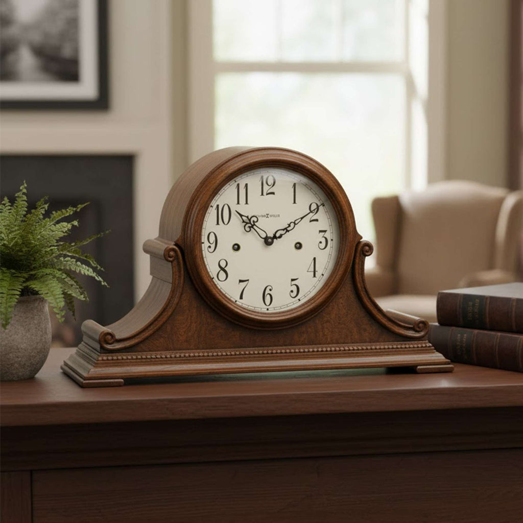 A vintage-style wooden clock with a round face, displayed on a table beside a potted plant and books.
