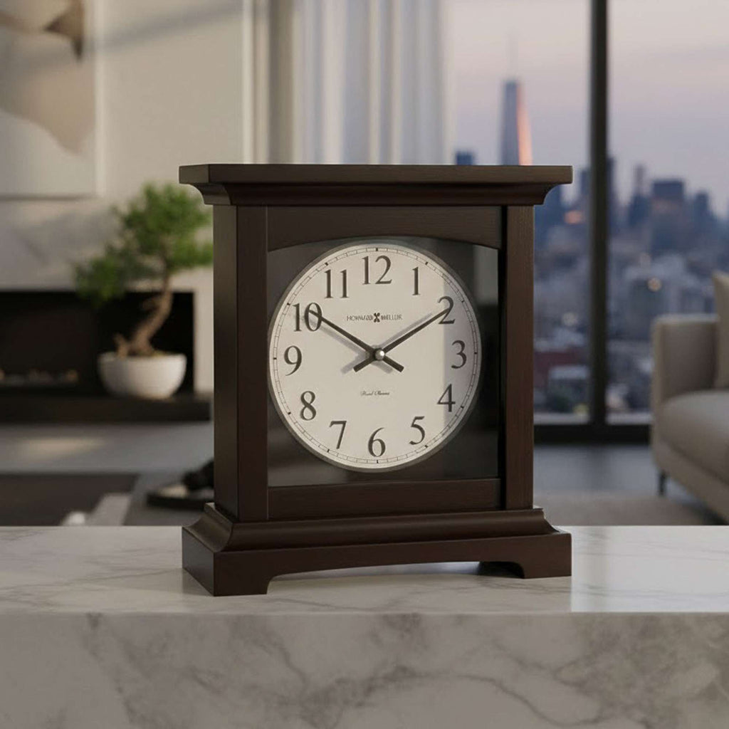 A wooden mantel clock with a white face and black numerals, displayed on a marble surface with a city skyline in the background.