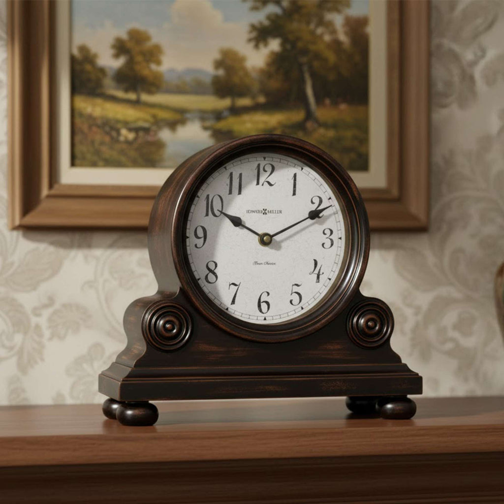 A vintage-style wooden clock with a round face and decorative base, displayed on a shelf in a cozy room.