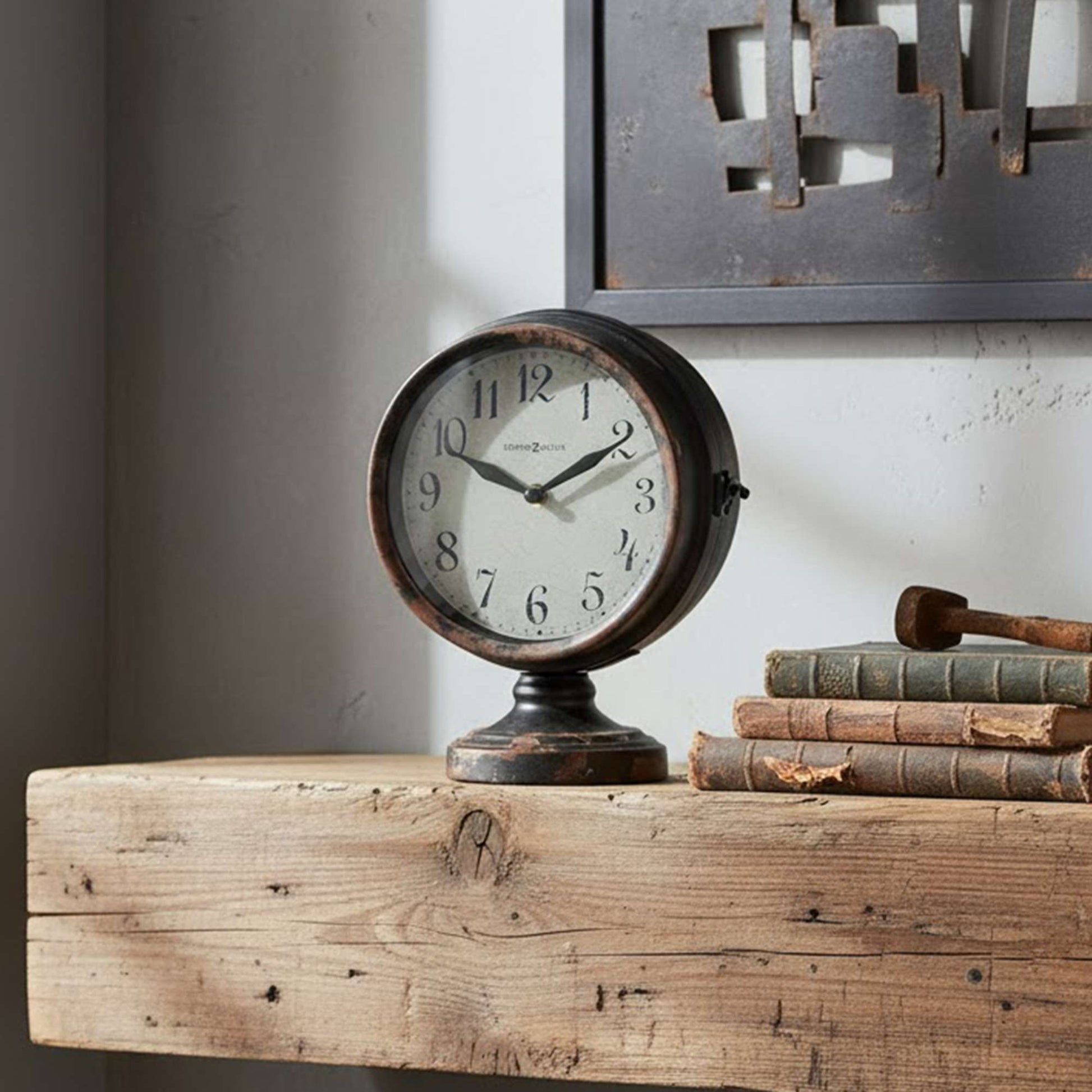 A vintage round clock on a rustic wooden shelf with stacked books.