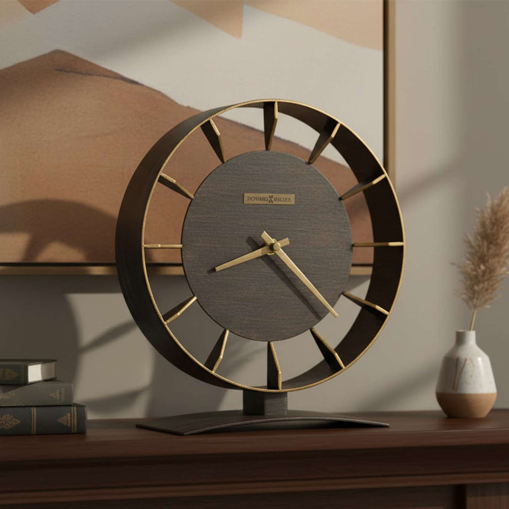 A stylish modern clock with a circular design, displaying a mix of wood and gold accents, placed on a wooden table.