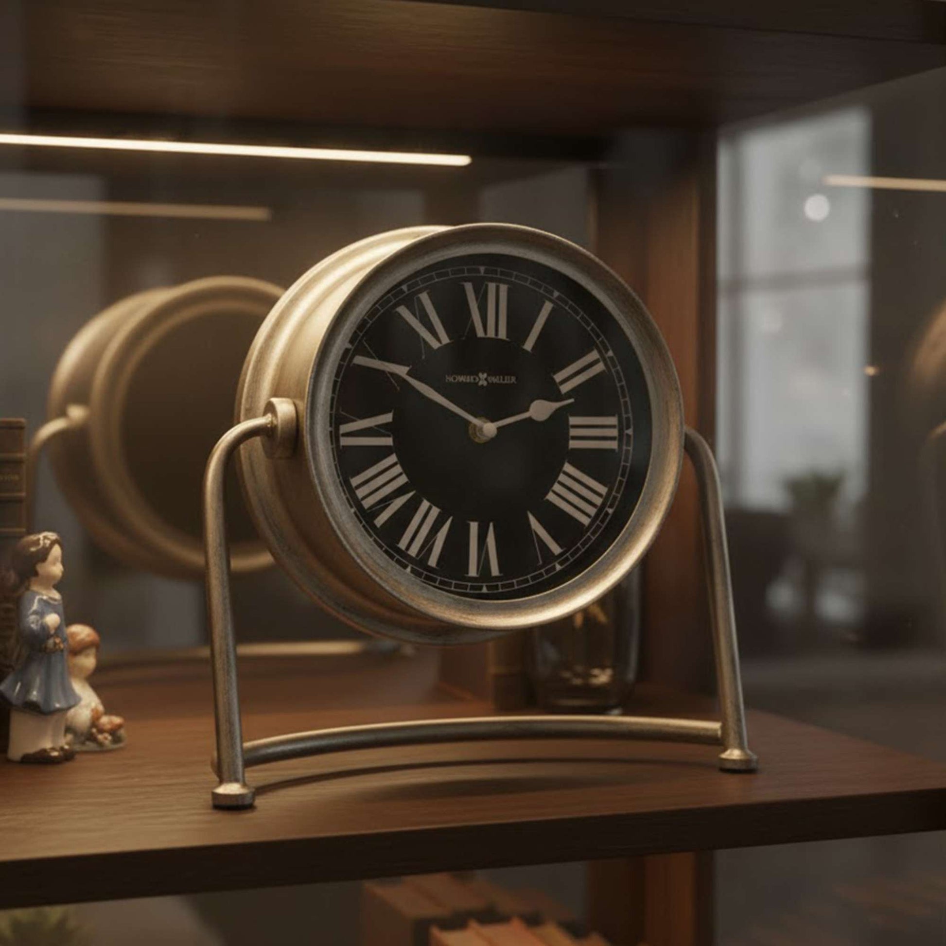 A vintage-style clock with a black face and Roman numerals displayed on a wooden shelf.