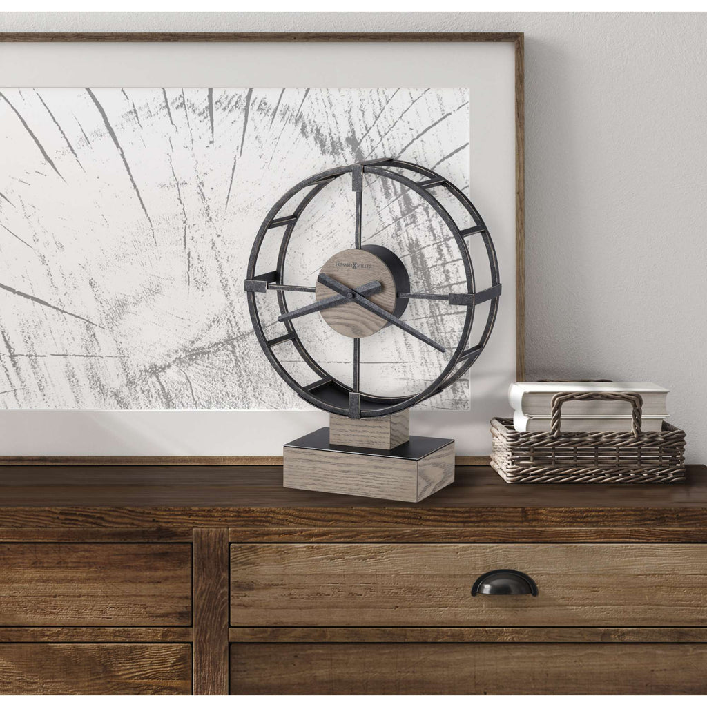 A decorative tabletop fan sculpture on a wooden dresser with abstract wall art in the background.