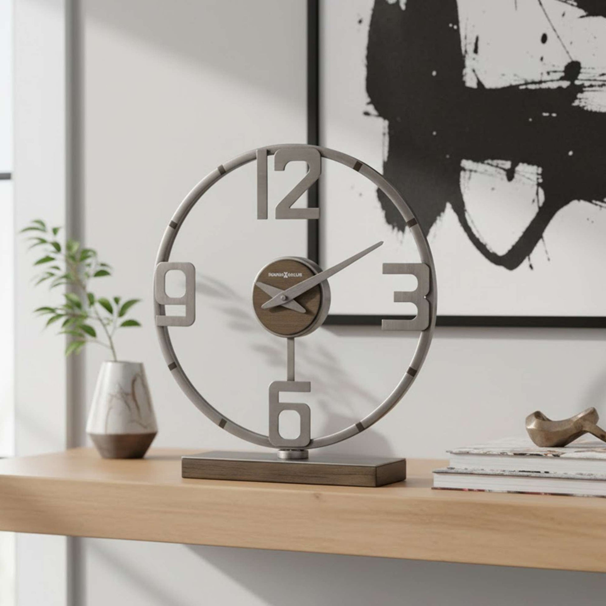 Modern round clock placed on a wooden shelf with decorative items.