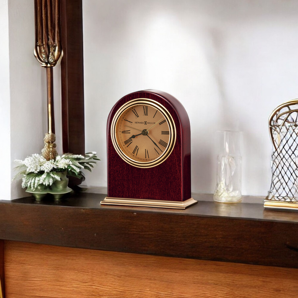 Elegant wooden mantel clock with a gold face on a shelf.