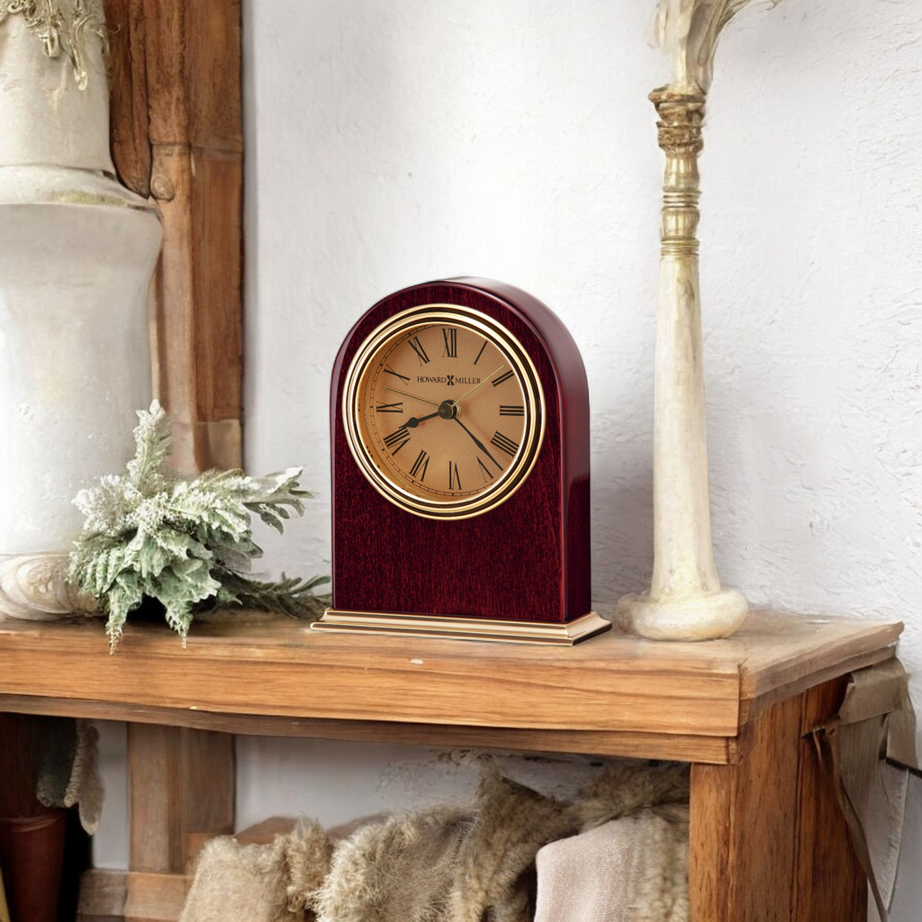 A vintage-style clock on a wooden shelf, surrounded by rustic decor.