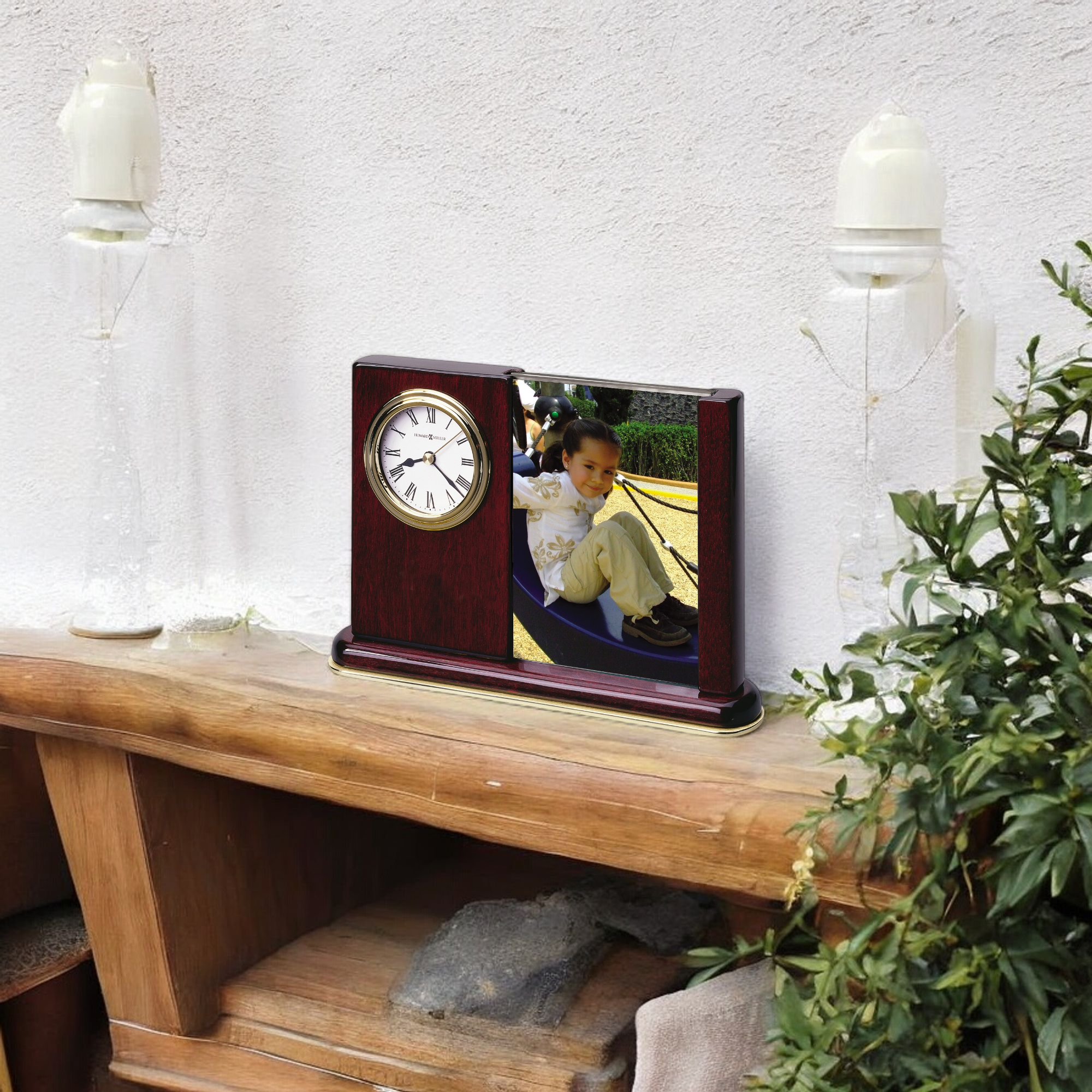 A decorative wooden clock displayed on a shelf, featuring a photo of a child playing.