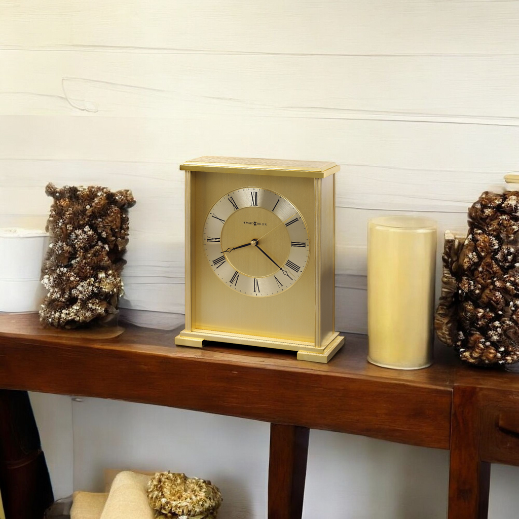 A gold-colored clock on a wooden shelf, surrounded by decorative items.