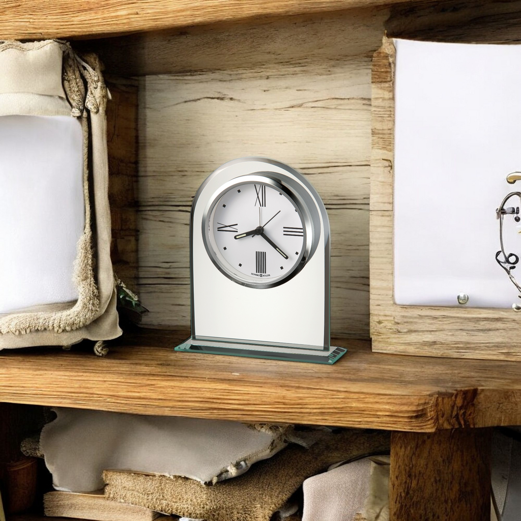 A decorative clock displayed on a wooden shelf next to neatly arranged fabric.