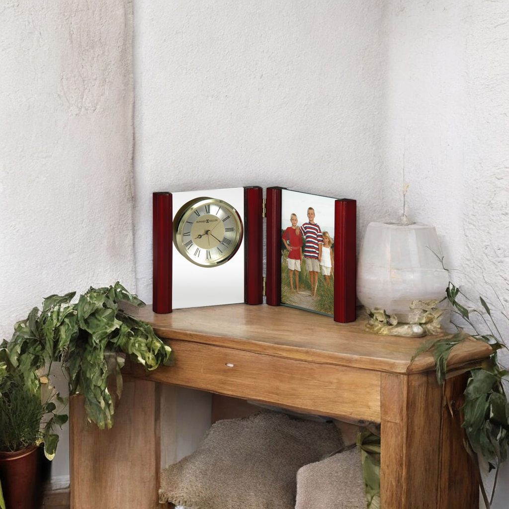 A wooden table with a clock and a photo frame displaying a family picture.