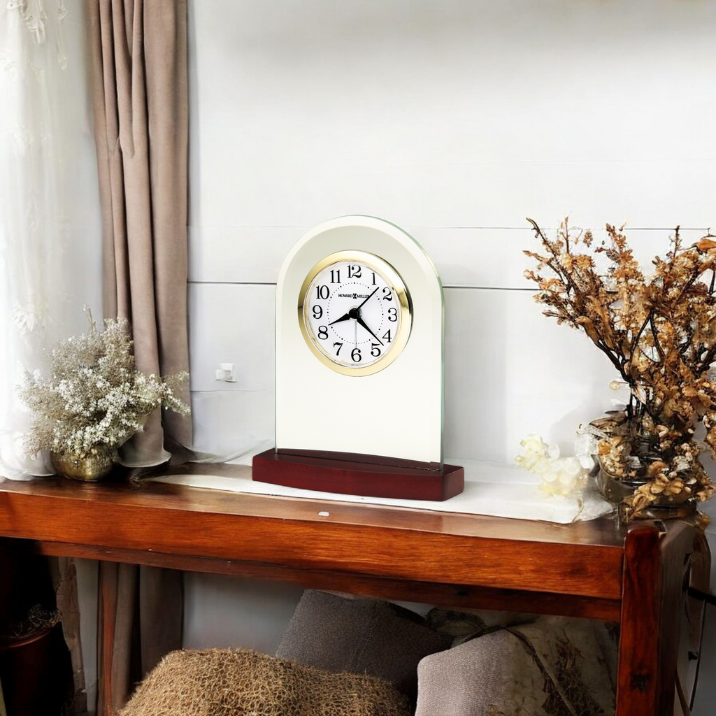 A vintage-style clock on a wooden table with decorative plants.