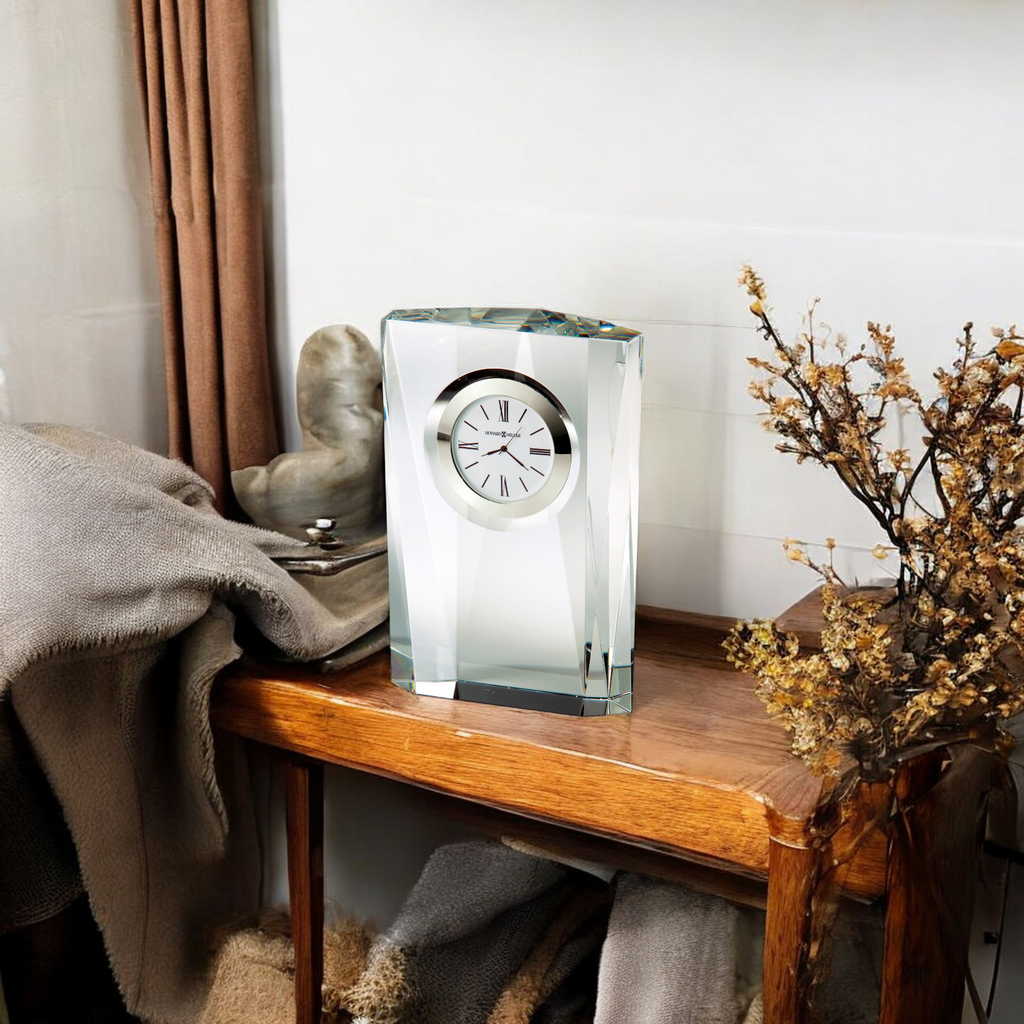 A transparent clock displayed on a wooden table next to decorative items.
