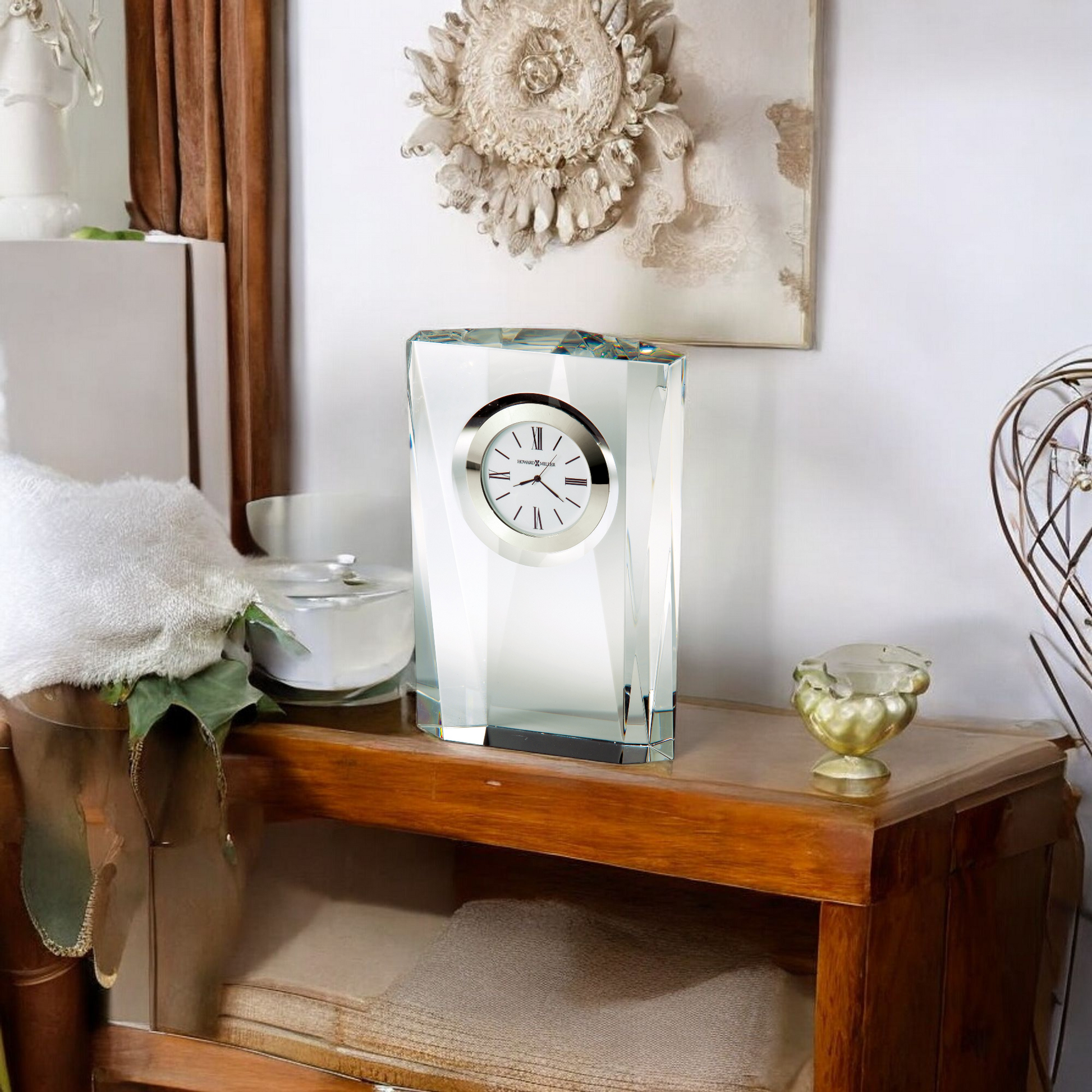 Elegant glass clock on a wooden shelf with decorative items.