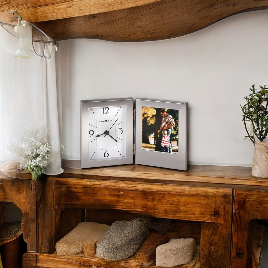 A stylish clock and a photo frame displayed on a wooden shelf with decorative elements.