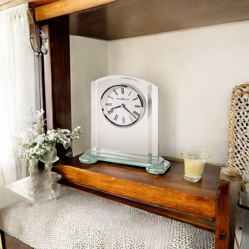 A decorative clock displayed on a wooden shelf with flowers and a candle.