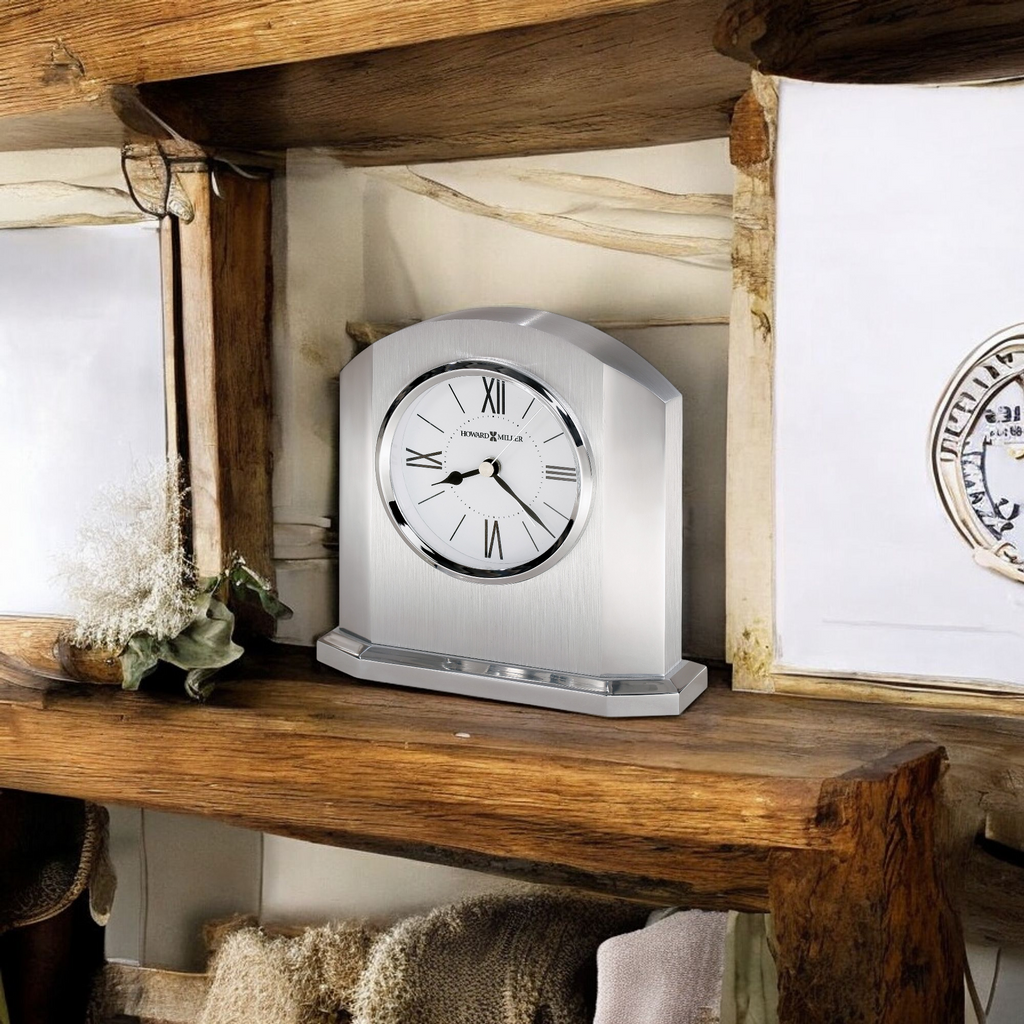 A silver clock on a wooden shelf with decorative elements.