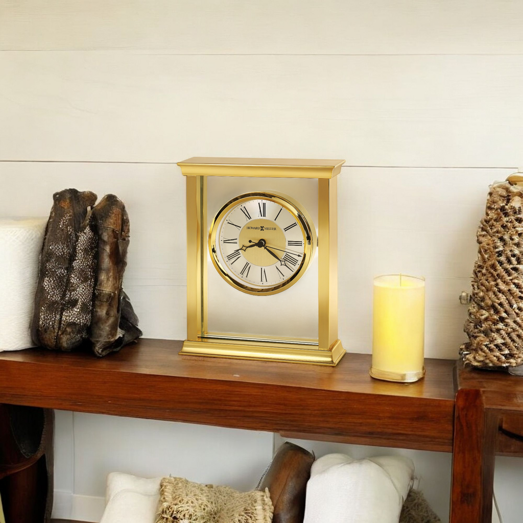 A decorative gold clock on a wooden shelf with candles and textured decor.
