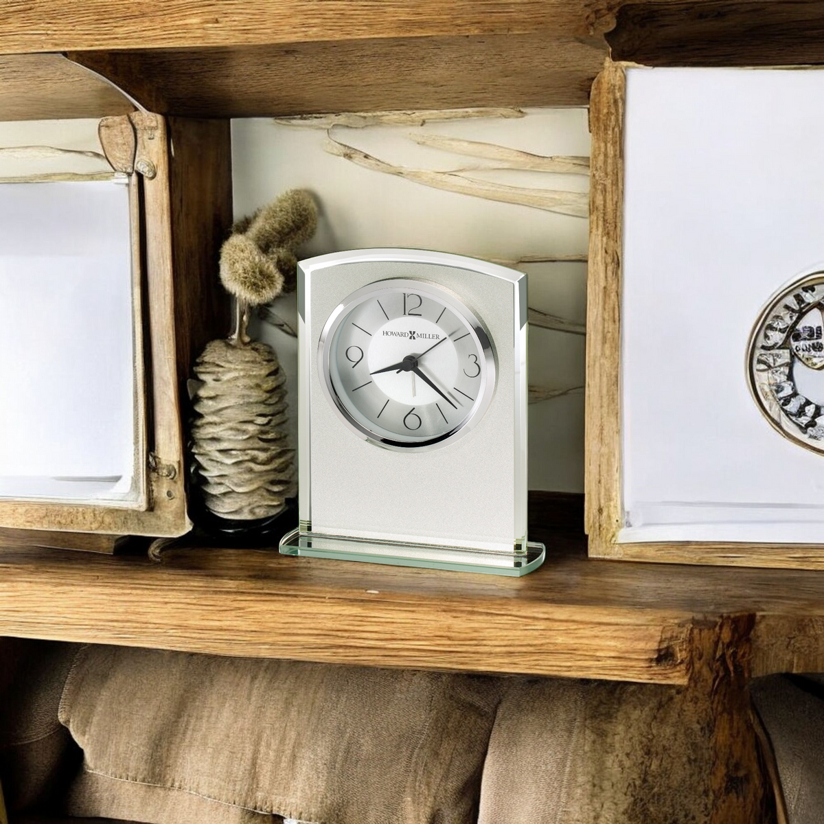A decorative clock displayed on a wooden shelf among other decor items.
