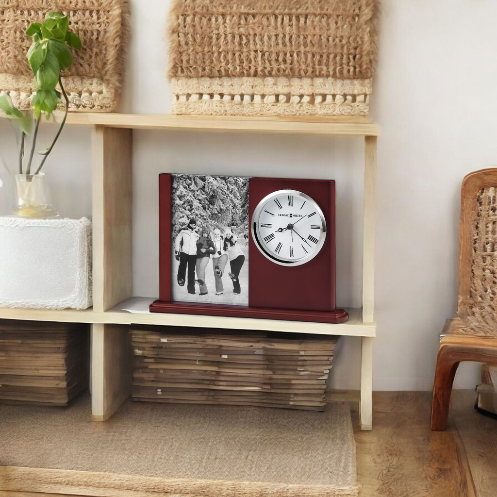 A vintage-style clock with a black and white photo, displayed on a wooden shelf with plants and woven baskets.
