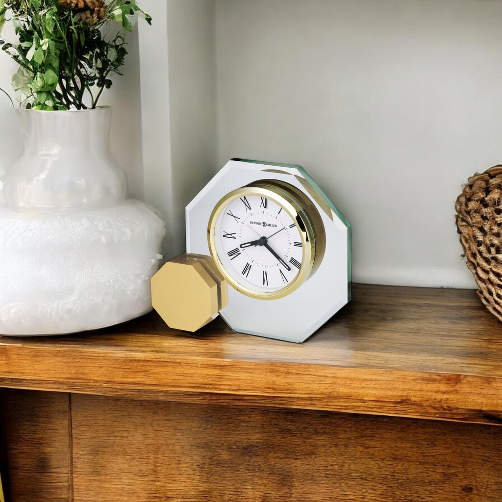Stylish octagonal clock on a wooden shelf with decorative items.