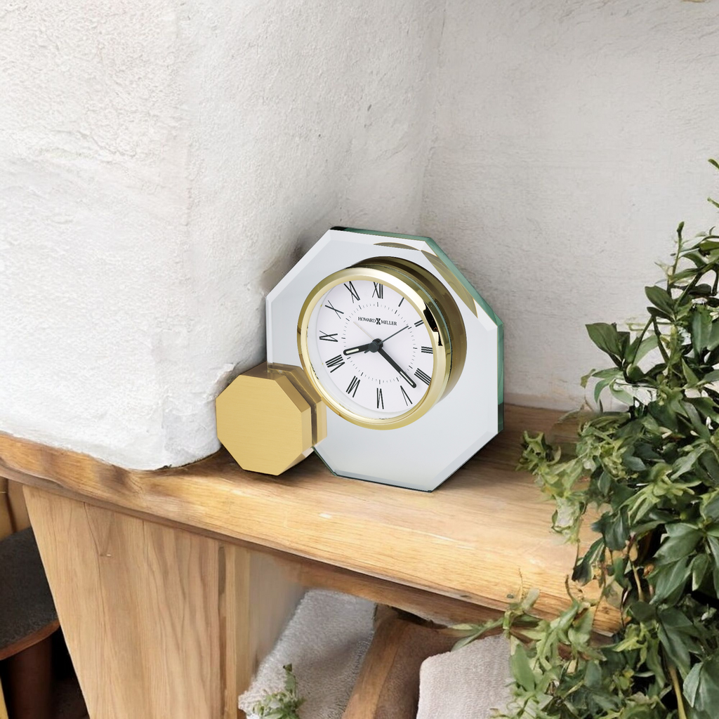 A modern octagonal clock with a gold accent sitting on a wooden shelf.