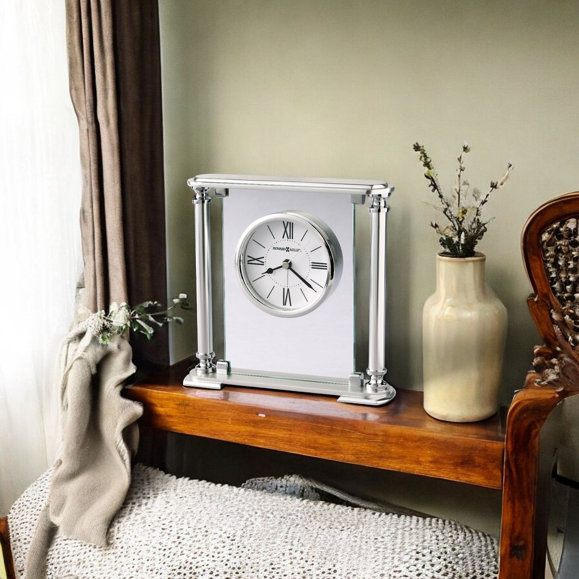 A decorative clock on a wooden shelf with a vase and plant.
