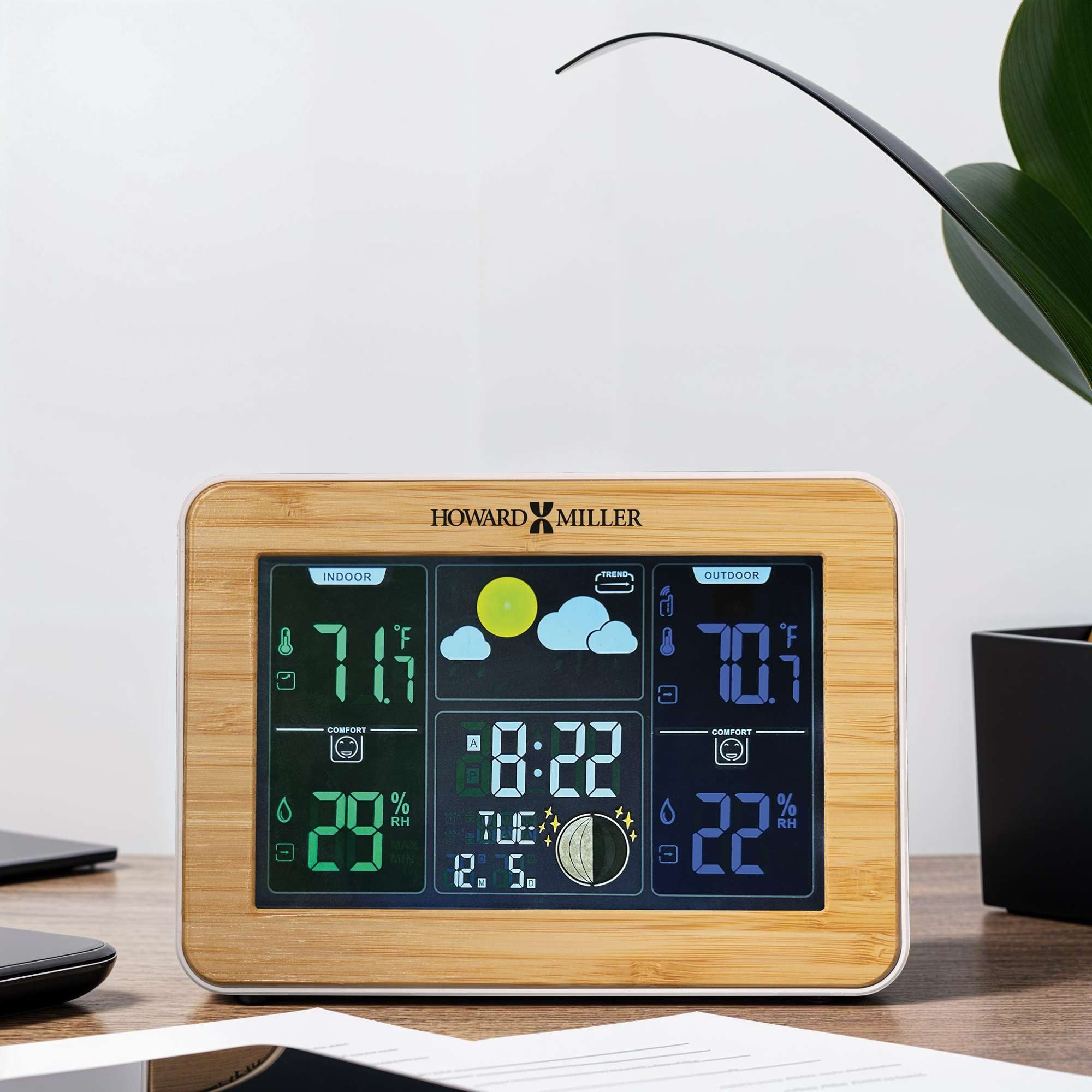 Digital weather station on a desk showing temperature and time