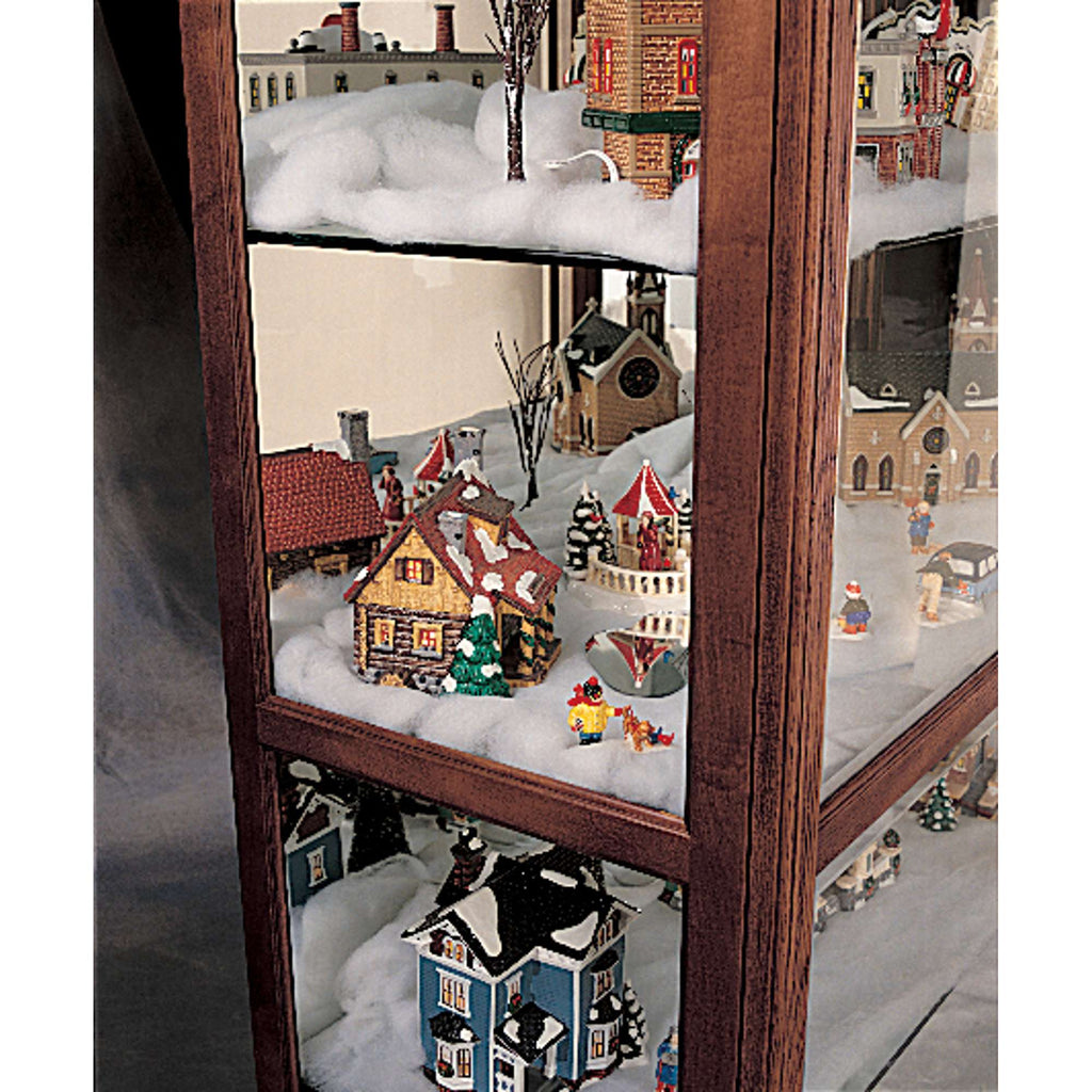 A display case filled with miniature holiday village scenes, featuring snow and decorative houses.