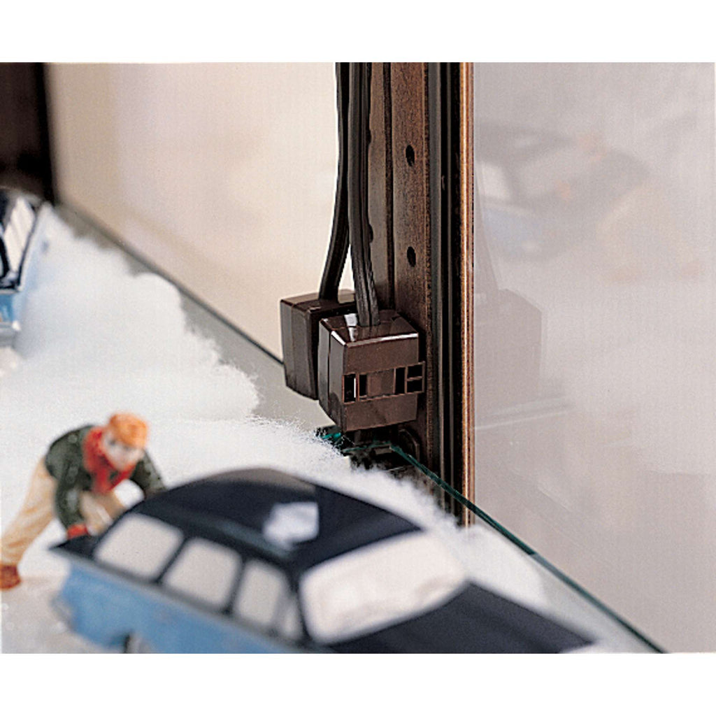 Model train setup with a man adjusting scenery and a close-up of electrical components.